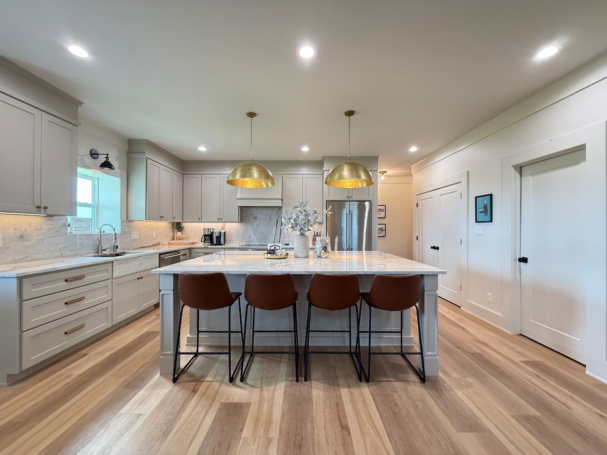 Moonlight Marsh chef's kitchen with marble island, Thermador appliances and gold pendant lights